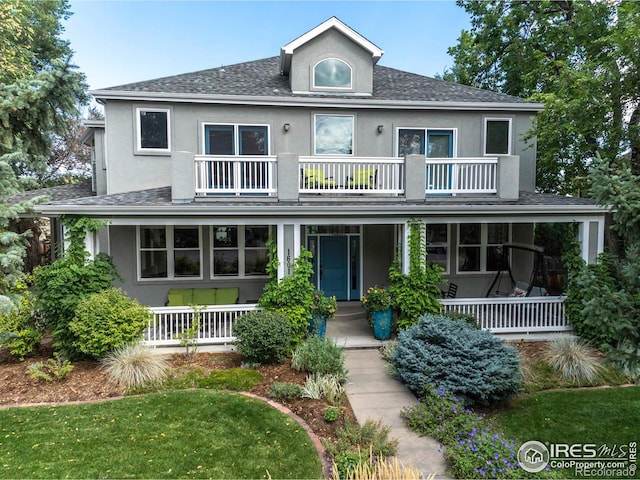 view of front of home with covered porch, a balcony, and a front yard