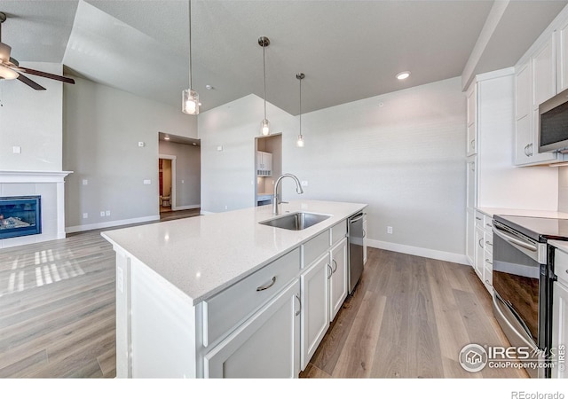 kitchen featuring white cabinetry, a center island with sink, stainless steel appliances, sink, and pendant lighting