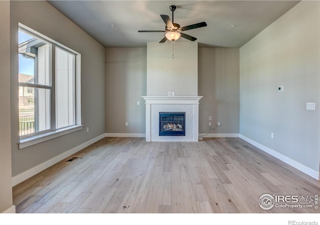 unfurnished living room featuring a fireplace, ceiling fan, and light hardwood / wood-style floors