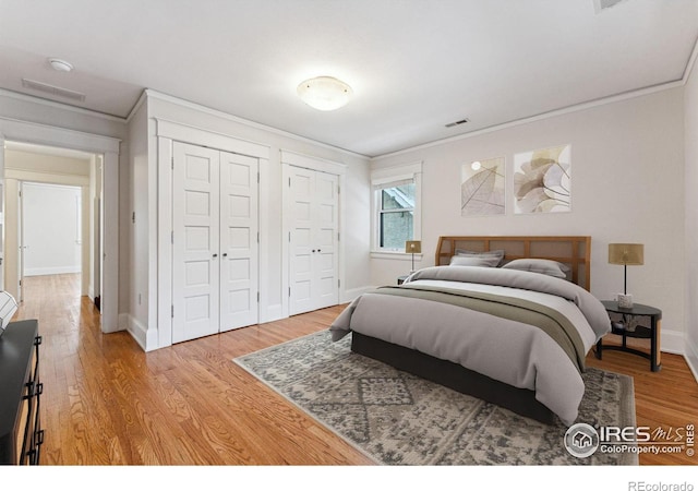 851 14th St, Boulder, CO 80302 - bedroom with ornamental molding, two closets, light wood finished floors, and visible vents