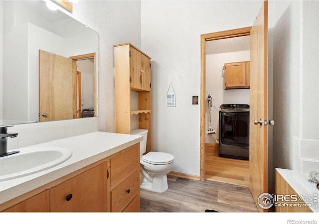 bathroom featuring toilet, washer / dryer, backsplash, hardwood / wood-style floors, and vanity