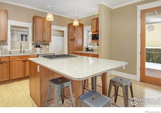 kitchen featuring hanging light fixtures, sink, a kitchen island, and a breakfast bar area