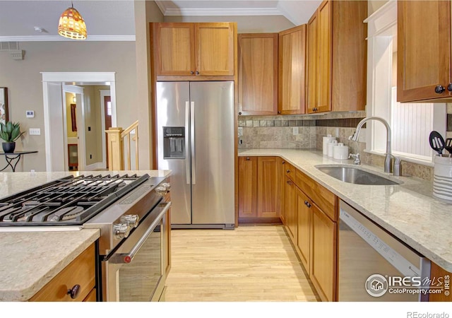 kitchen with appliances with stainless steel finishes, sink, decorative light fixtures, light hardwood / wood-style floors, and crown molding