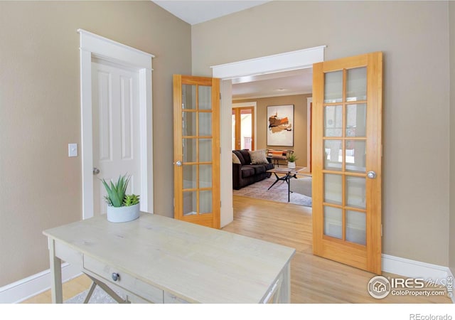 office with light wood-type flooring and french doors