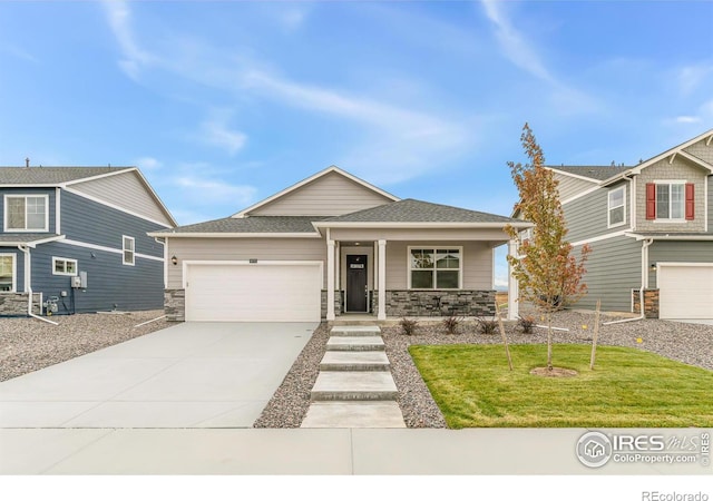 view of front facade featuring driveway, covered porch, an attached garage, and stone siding