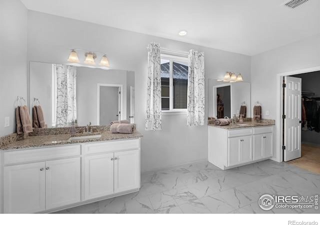 887 Sundance Ln, Erie, CO 80516 - full bathroom with two vanities, marble finish floors, and a walk in closet