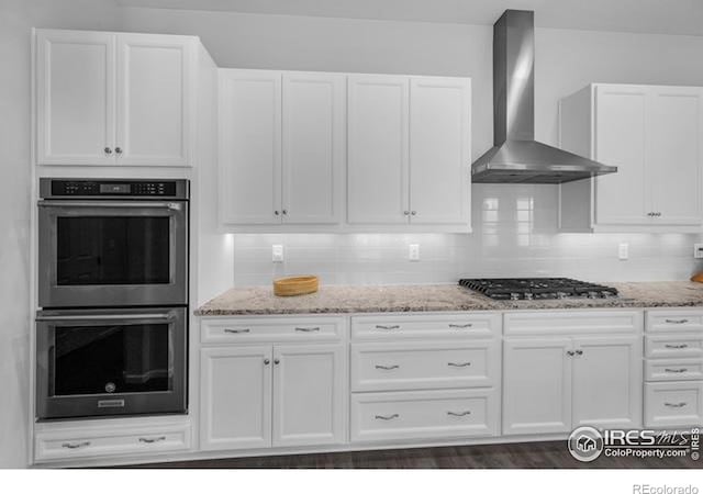 887 Sundance Ln, Erie, CO 80516 - kitchen featuring wall chimney exhaust hood, appliances with stainless steel finishes, light stone countertops, and white cabinetry