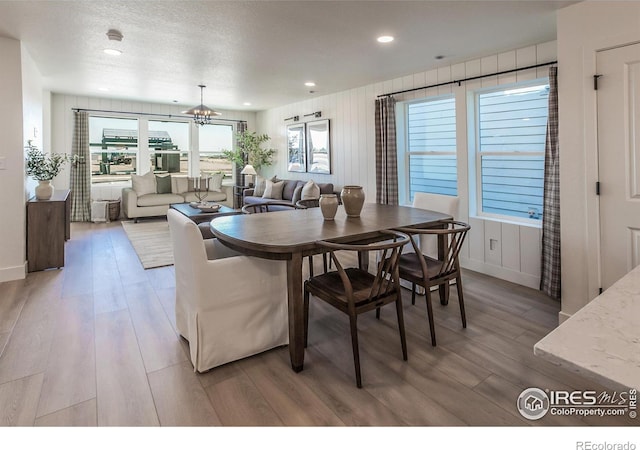 dining space featuring light hardwood / wood-style floors, a chandelier, and a textured ceiling