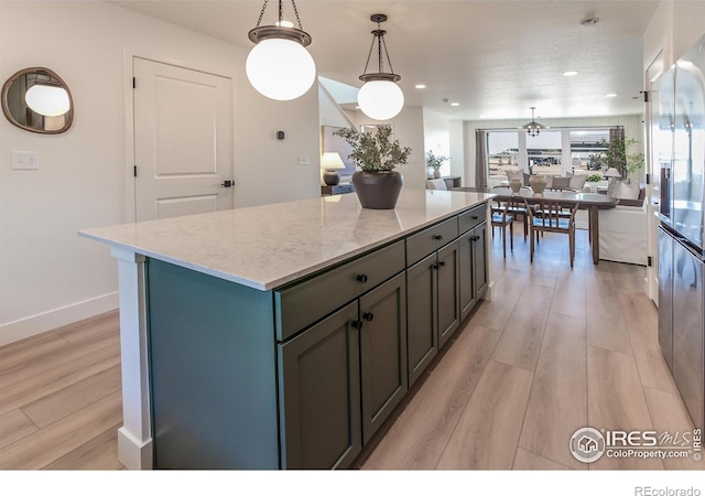 kitchen featuring light hardwood / wood-style flooring, pendant lighting, light stone countertops, and a center island