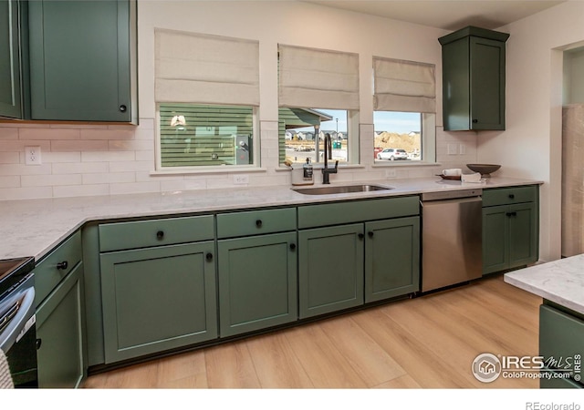 kitchen featuring light wood-type flooring, green cabinets, sink, backsplash, and dishwasher