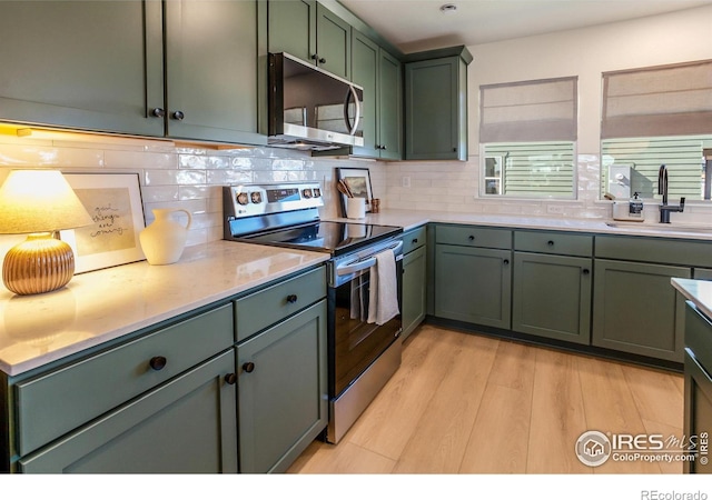 kitchen featuring appliances with stainless steel finishes, sink, green cabinetry, and tasteful backsplash