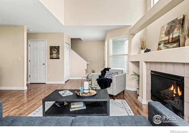 living area with a fireplace, baseboards, and wood finished floors