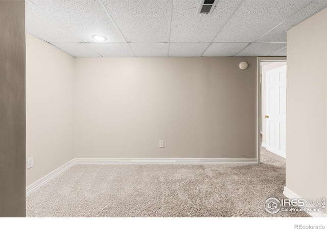 carpeted spare room featuring baseboards, visible vents, and a drop ceiling