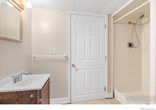 full bath featuring a drop ceiling, vanity, and walk in shower