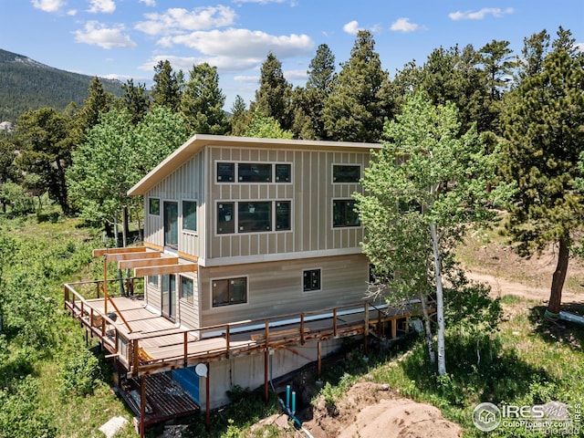 rear view of property featuring a deck with mountain view and a pergola