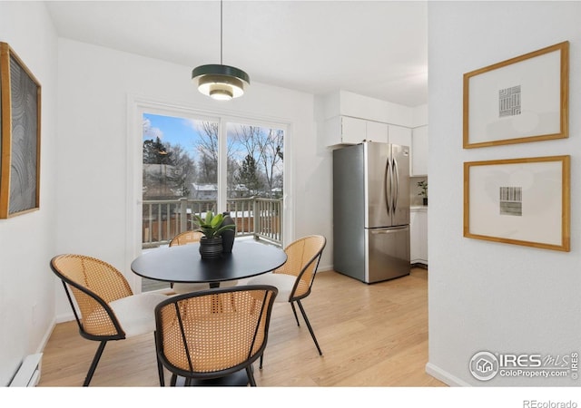 dining room with baseboard heating, light wood-style flooring, and baseboards