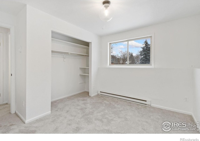 unfurnished bedroom with light carpet, baseboards, a baseboard heating unit, and a closet