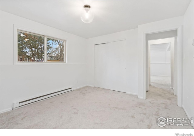 unfurnished bedroom with light carpet, baseboards, baseboard heating, and a closet