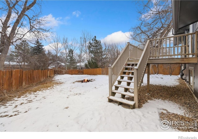 yard covered in snow with a deck, stairway, and a fenced backyard