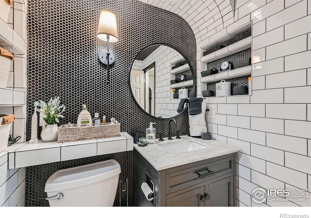 bathroom featuring toilet, tile walls, backsplash, and vanity