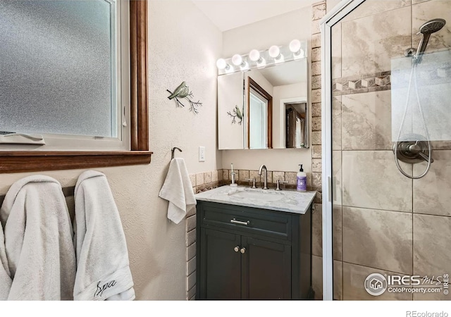 bathroom with a tile shower and vanity