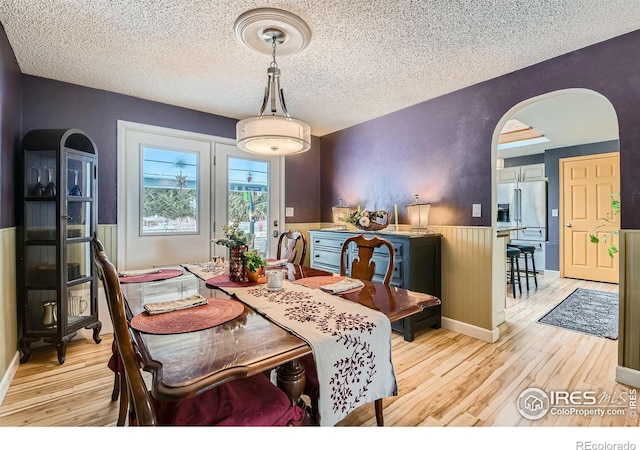 dining space with a textured ceiling and light hardwood / wood-style flooring