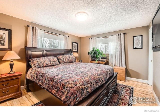 bedroom featuring multiple windows, a textured ceiling, and light hardwood / wood-style flooring