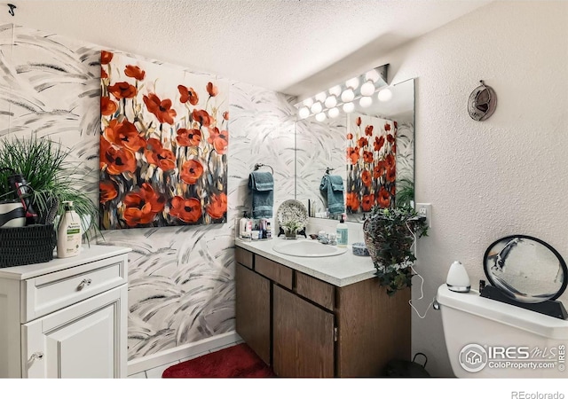 bathroom with a textured ceiling, toilet, and vanity