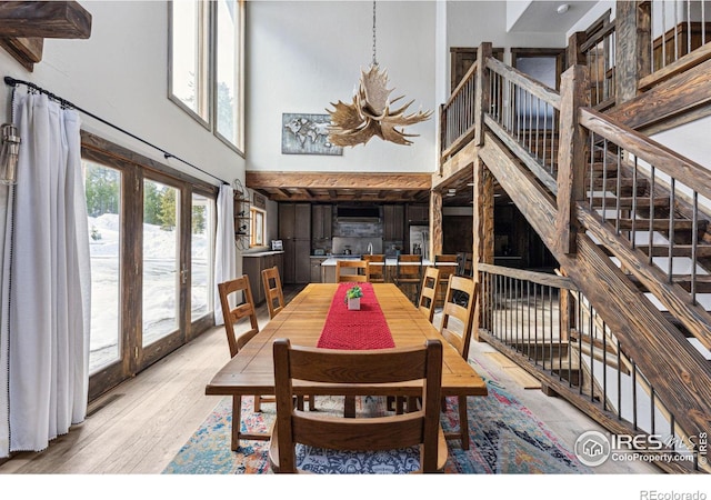 dining space with hardwood / wood-style floors, an inviting chandelier, and a high ceiling