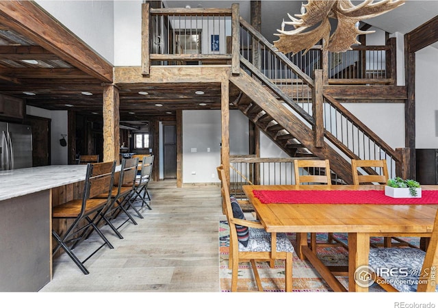 dining area featuring a towering ceiling and light hardwood / wood-style flooring