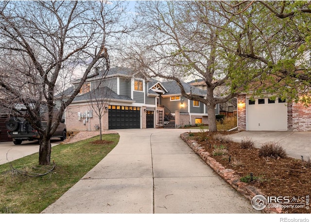 shingle-style home featuring brick siding, a garage, and driveway