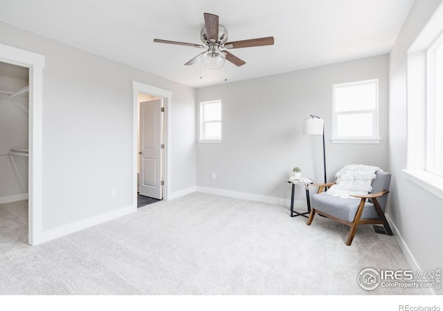 living area with light carpet, a ceiling fan, and baseboards