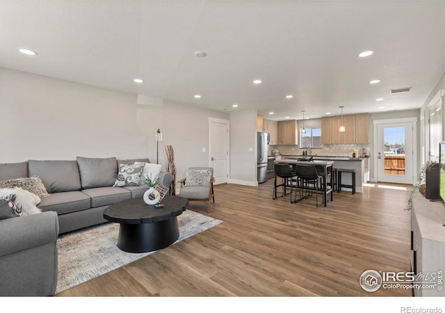 living area featuring light wood-style floors, recessed lighting, and visible vents