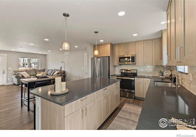 kitchen featuring open floor plan, appliances with stainless steel finishes, dark countertops, and a kitchen island