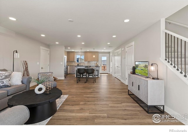 living area with light wood-style flooring, stairway, baseboards, and recessed lighting