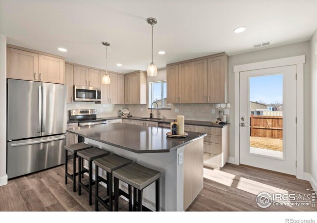 kitchen with visible vents, dark countertops, appliances with stainless steel finishes, hanging light fixtures, and a sink