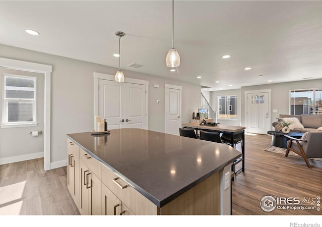 kitchen featuring open floor plan, dark countertops, a kitchen island, and pendant lighting