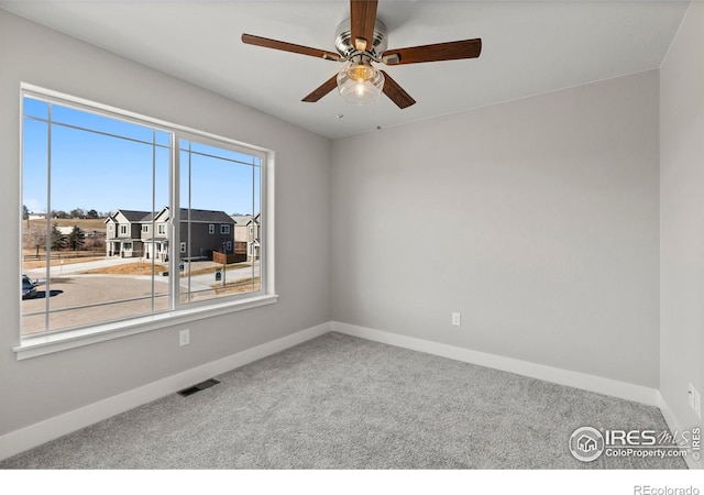 spare room with carpet, visible vents, a residential view, and baseboards