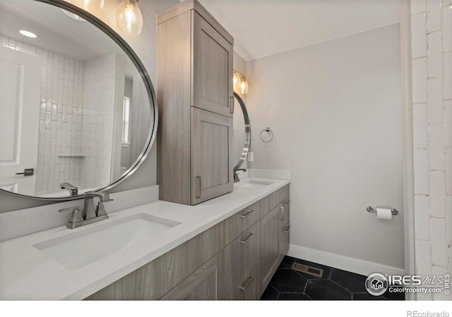 full bath featuring double vanity, tile patterned flooring, baseboards, and a sink