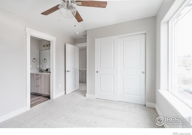 unfurnished bedroom featuring light carpet, baseboards, a closet, and ensuite bathroom