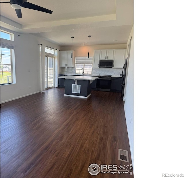 3510 Valleywood Ct, Johnstown, CO 80534 - kitchen featuring electric range oven, black microwave, stainless steel fridge, a tray ceiling, and dark wood-style flooring