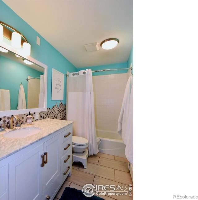 full bathroom featuring shower / tub combo with curtain, vanity, and toilet