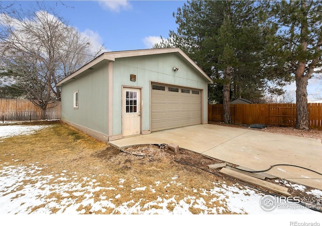 snow covered garage featuring a garage and fence