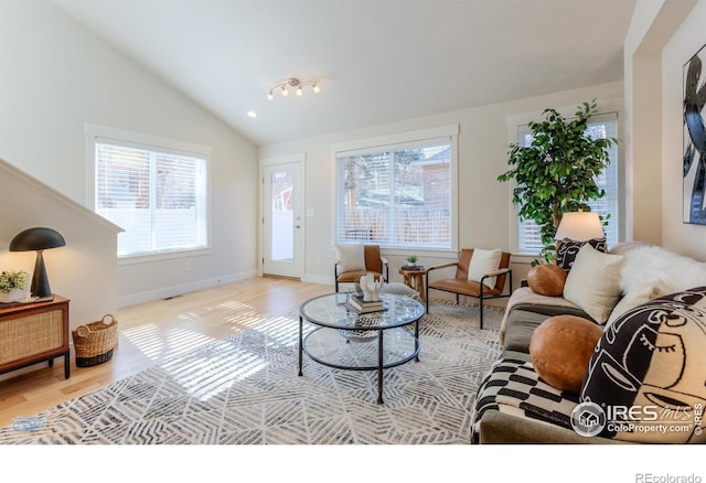 living room with vaulted ceiling, light wood-type flooring, and baseboards