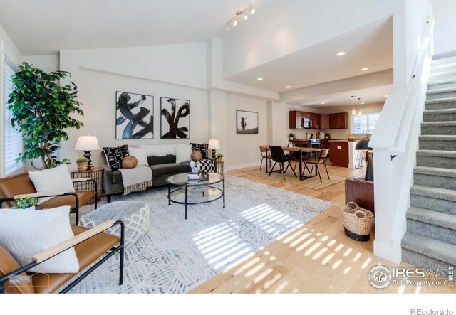 living area with baseboards, stairway, vaulted ceiling, light wood-type flooring, and recessed lighting