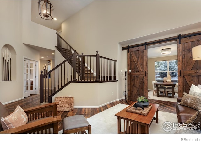 living room featuring wood finished floors, stairway, baseboards, and a barn door