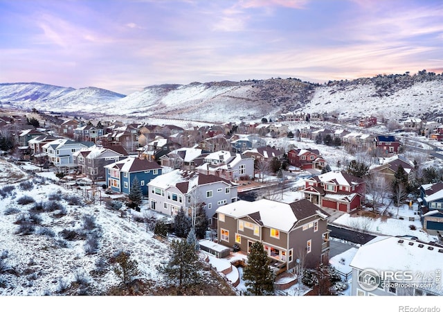 snowy aerial view featuring a residential view and a mountain view