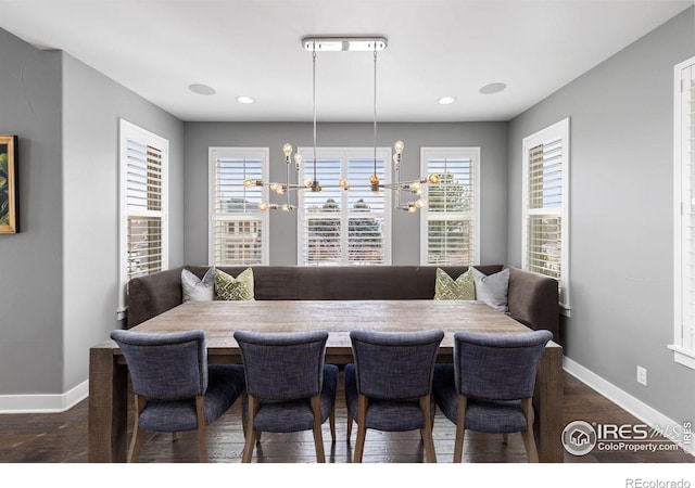 dining area featuring dark wood-type flooring, an inviting chandelier, and a wealth of natural light