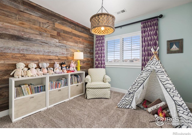 playroom with carpet and wood walls