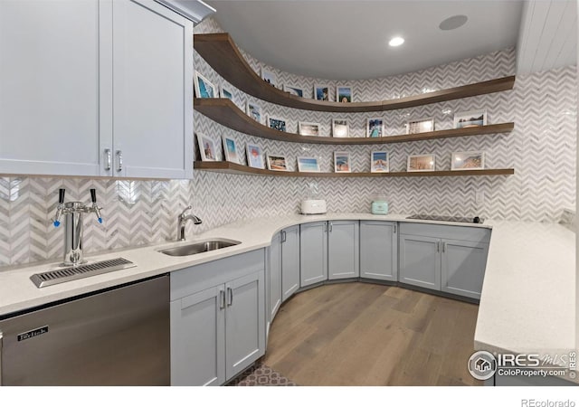 kitchen with tasteful backsplash, gray cabinetry, dishwashing machine, sink, and dark hardwood / wood-style floors